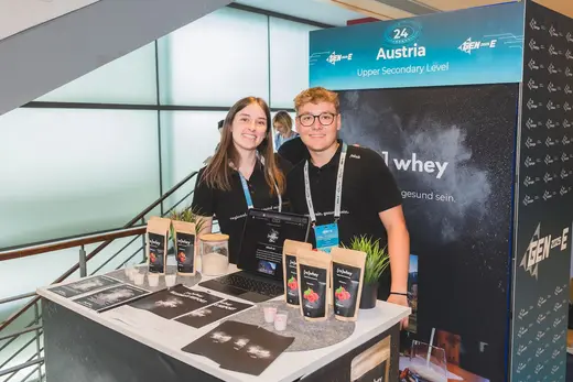 Zwei Schüler:innen der Junior Company [re]whey an ihrem Messestand beim europäischen Wettbewerb GEN-E 2025